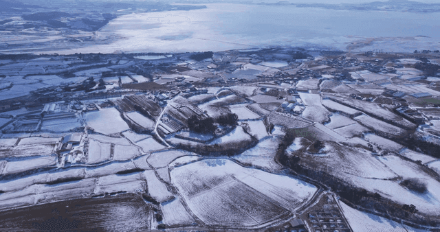 Snow-covered fields near tranquil lake