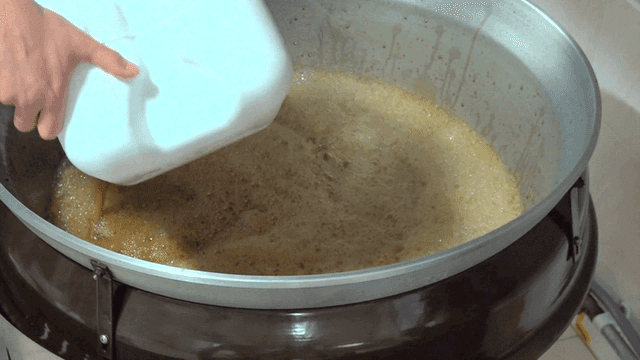 Soy sauce poured from large container into big pot