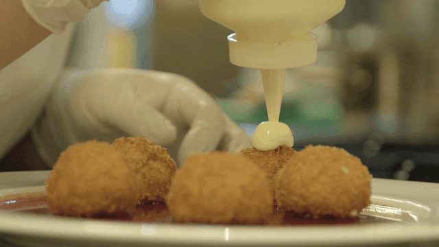 Sauce being applied to fried croquettes