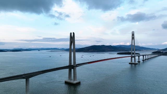 Long bridge over a calm sea with mountains