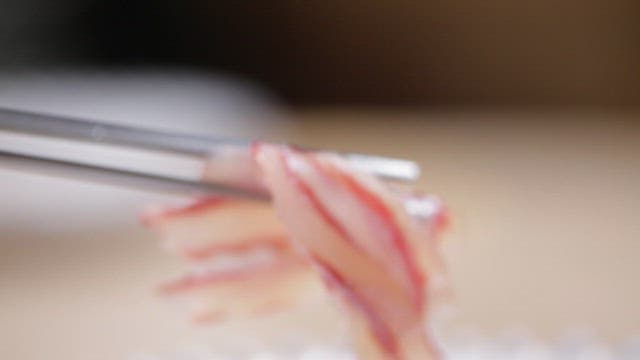 Sashimi of tingray dipped in red chili paste with chopsticks