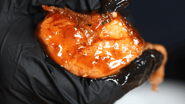 Spicy seasoned braised chicken held in gloved hands