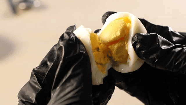 Hands cracking hard-boiled egg
