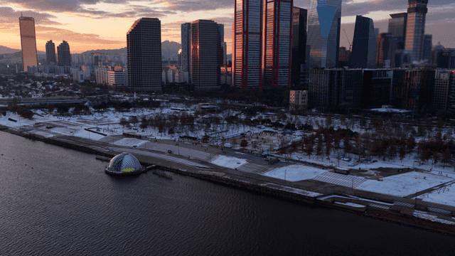 Snow-covered riverside park and city skyline