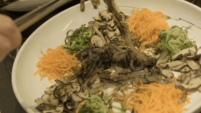 Tongs for scooping out jellyfish salad mixed with fresh vegetables