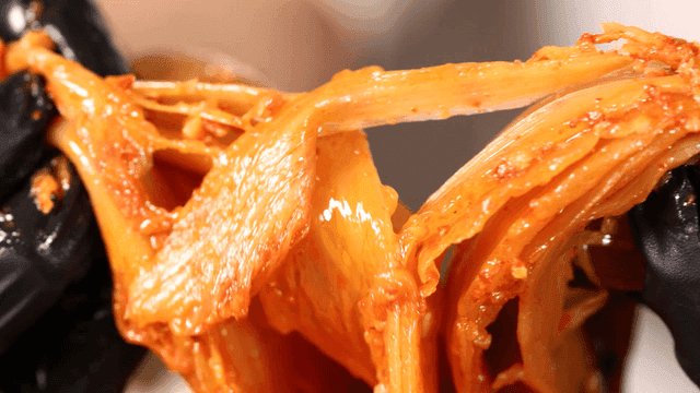 Aged kimchi torn apart and eaten with gloved hands