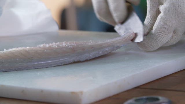 Peeling fresh fish fillets on a cutting board