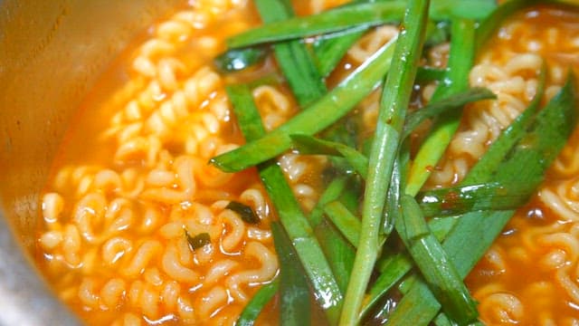 금속 냄비에 담긴 파를 얹은 뜨거운 라면