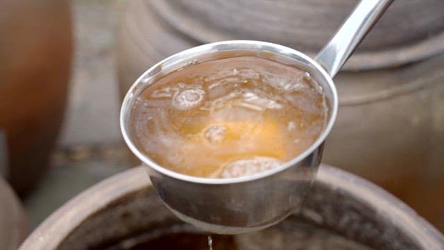 국자를 사용하여 장독 안에 간장을 붓는 모습