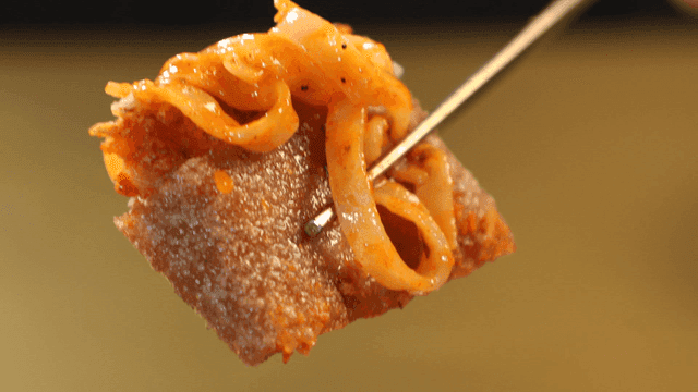 Buckwheat pancake with kimchi and chopsticks holding Bibi Kalguksu noodles