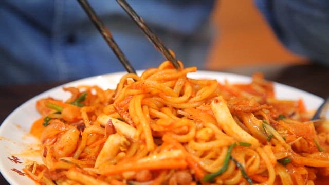 Chopstickful of spicy stir-fried Jjamppong with plenty of squid and vegetables