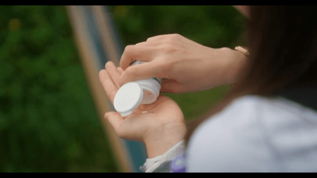 야외에서 분홍색 알약을 급하게 먹는 여학생