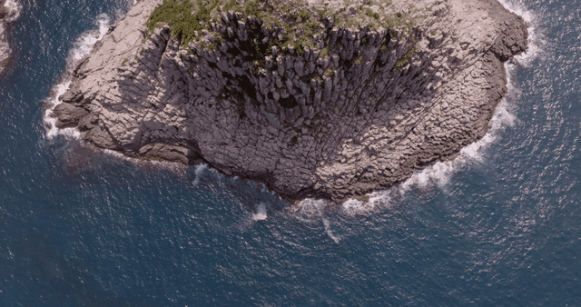 바다 파도에 둘러싸인 바위섬