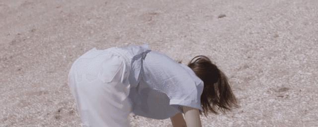 Woman startled by something on the beach and running away