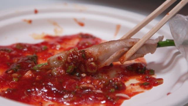 맛있게 구워진 대패삼겹살과 아스파라거스를 소스에 찍는 모습