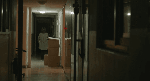 어두운 복도에서 상자를 나르는 여성