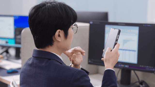 사무실 책상에서 스마트폰을 사용하는 남성