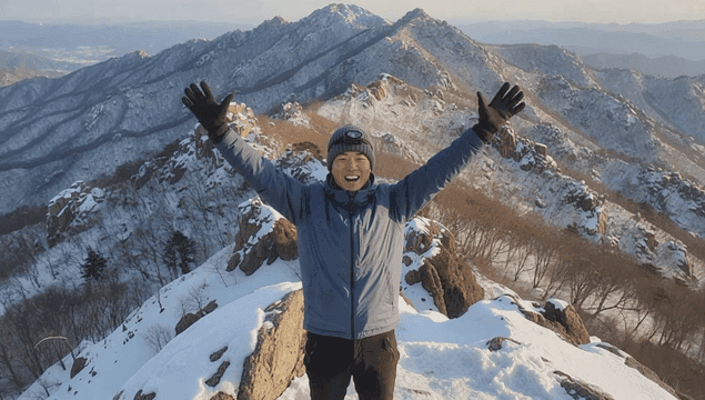 겨울 산 정상에 올라 만세를 하는 남자