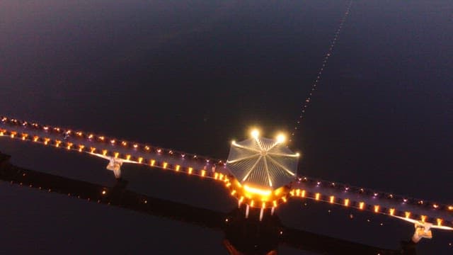 Illuminated bridge over calm river at night