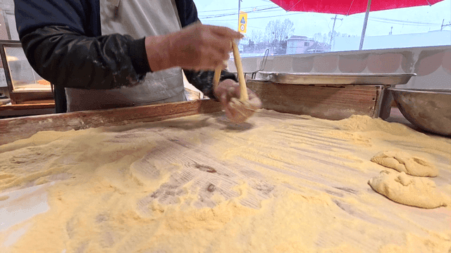 밀가루 위에서 꽈배기를 빠르게 마는 제빵사