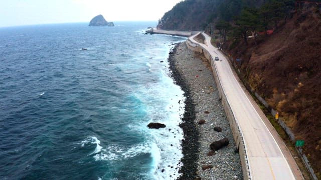 Coastal road winding alongside the ocean and mountains.