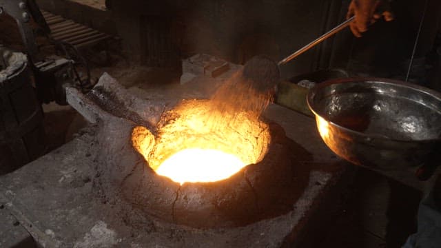 Worker handling molten metal in a workshop