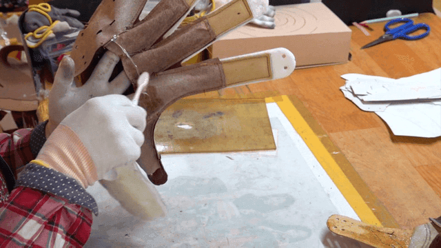 Worker applying chemical with toothbrush on leather gloves