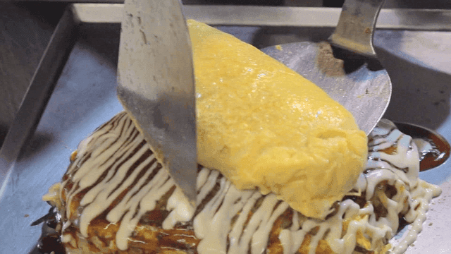 Omelette being placed on okonomiyaki
