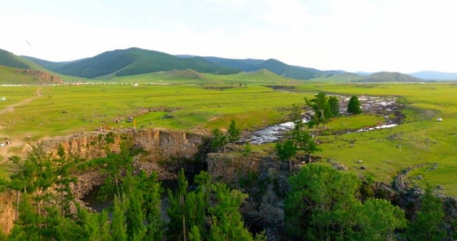 Vast green landscape with a rocky cliff