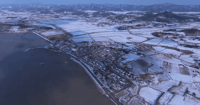 Snow-covered Hanok village and fields by sea