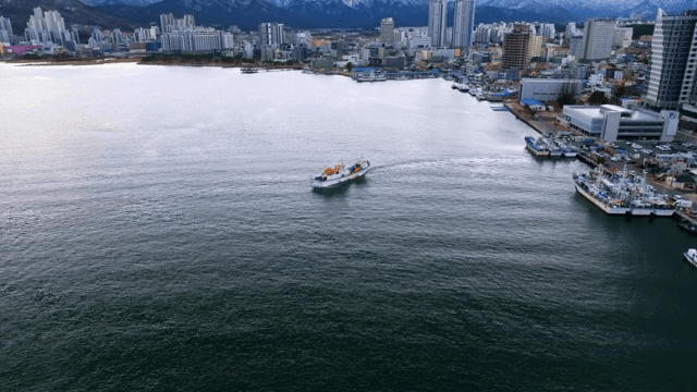 번화한 도시 항구 근처를 항해하는 배