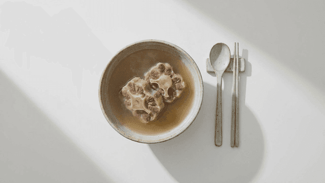 A bowl of oxtail soup with utensils