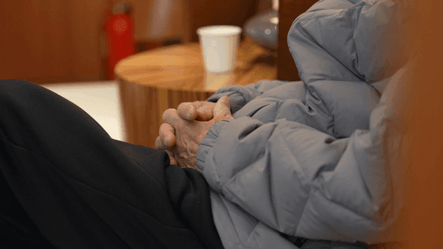 Old man wearing padded jacket sitting and resting