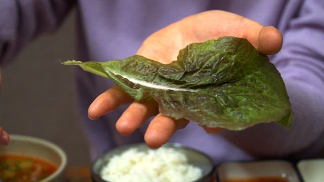 상추에 수육과 마늘, 고추, 밥을 올려 쌈을 만드는 모습