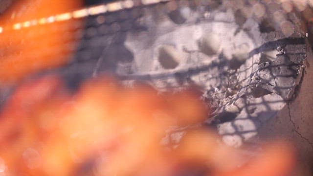 Grilling marinated pork ribs on a grill over burning charcoal