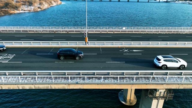 Vehicles Running on a Bridge over a Quiet River