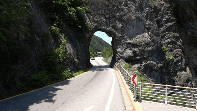 Road passing through rocky tunnel with car