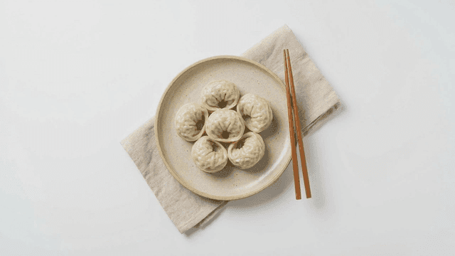 Steamed dumplings on a plate with chopsticks