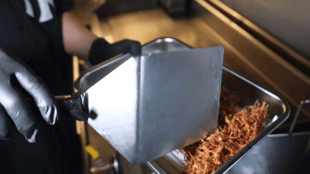 Enoki mushroom fritters spread onto frying tray with spatula
