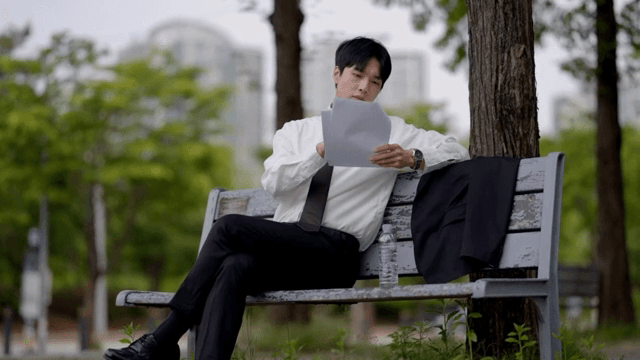 Office worker reading documents on bench