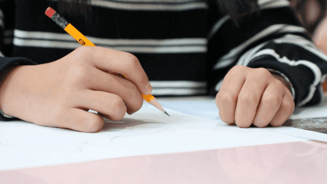 Elementary school students drawing on paper with pencils
