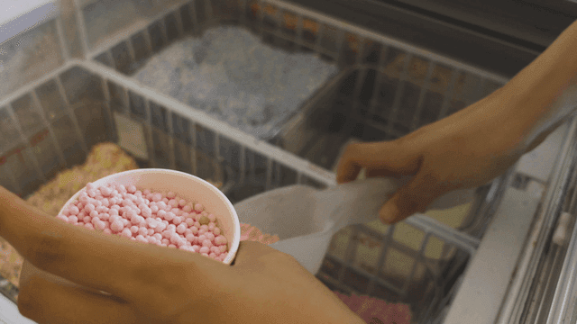 Hand pouring pink bead ice cream into cup