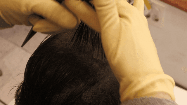 Hair being styled with a comb and gloves