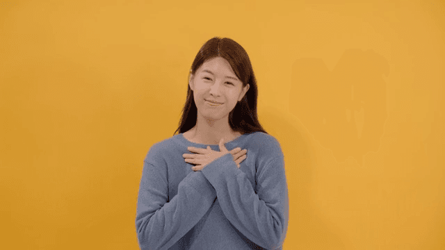 진심 어린 미소를 지으며 가슴에 손을 얹고 감사함을 표현하는 여성