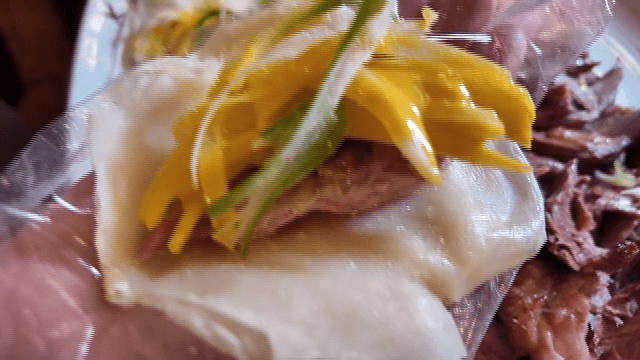 Wheat pancake wrap topped with shredded green onions and smoked duck
