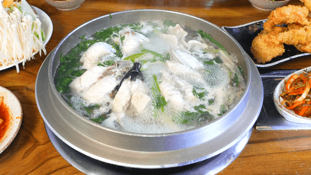 Clear pufferfish soup boiling with side dishes