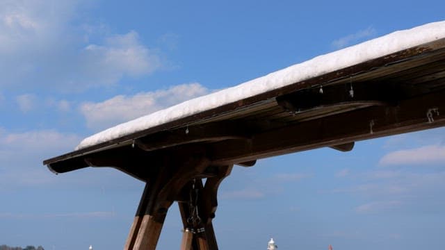 Snow-covered wooden roof with clear sky in the background