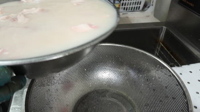 Straining meat through a sieve in a restaurant kitchen
