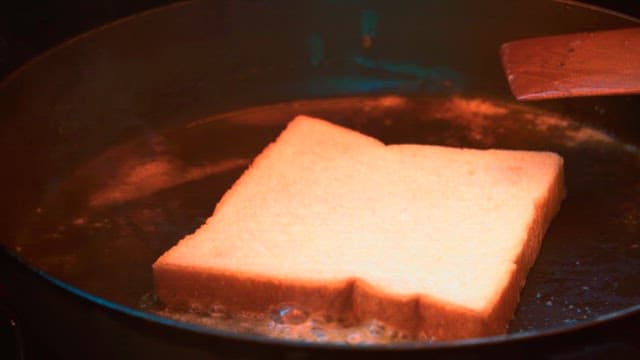 Toasting golden brown toast with bread and a spatula in a frying pan