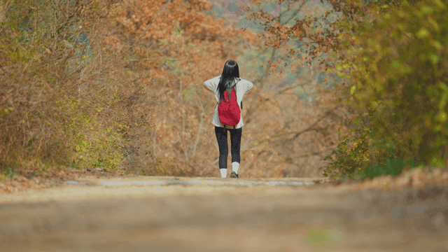 Young woman descending autumn mountain trail